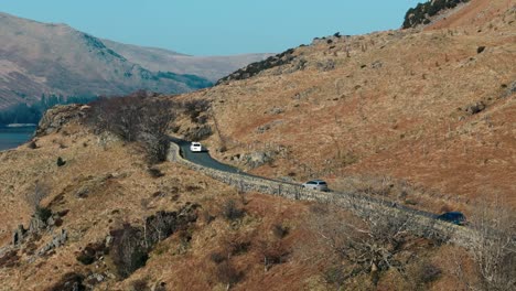Tracking aerial of car driving through Lake District farmland in spring light, exploration and tourism