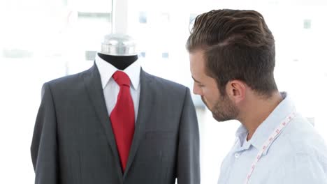 hermoso sastre usando la tableta al lado del traje en el maniquí