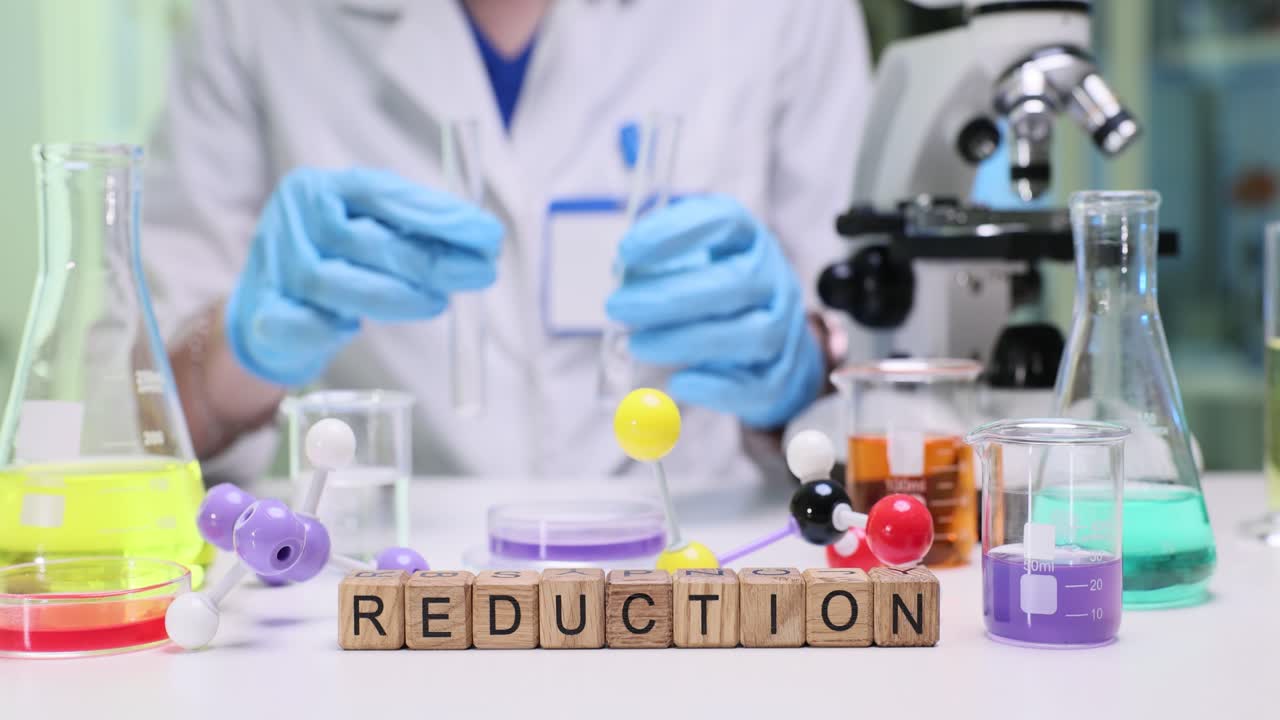 Scientist Handling Test Tubes in a Laboratory with 'Reduction' Word Blocks