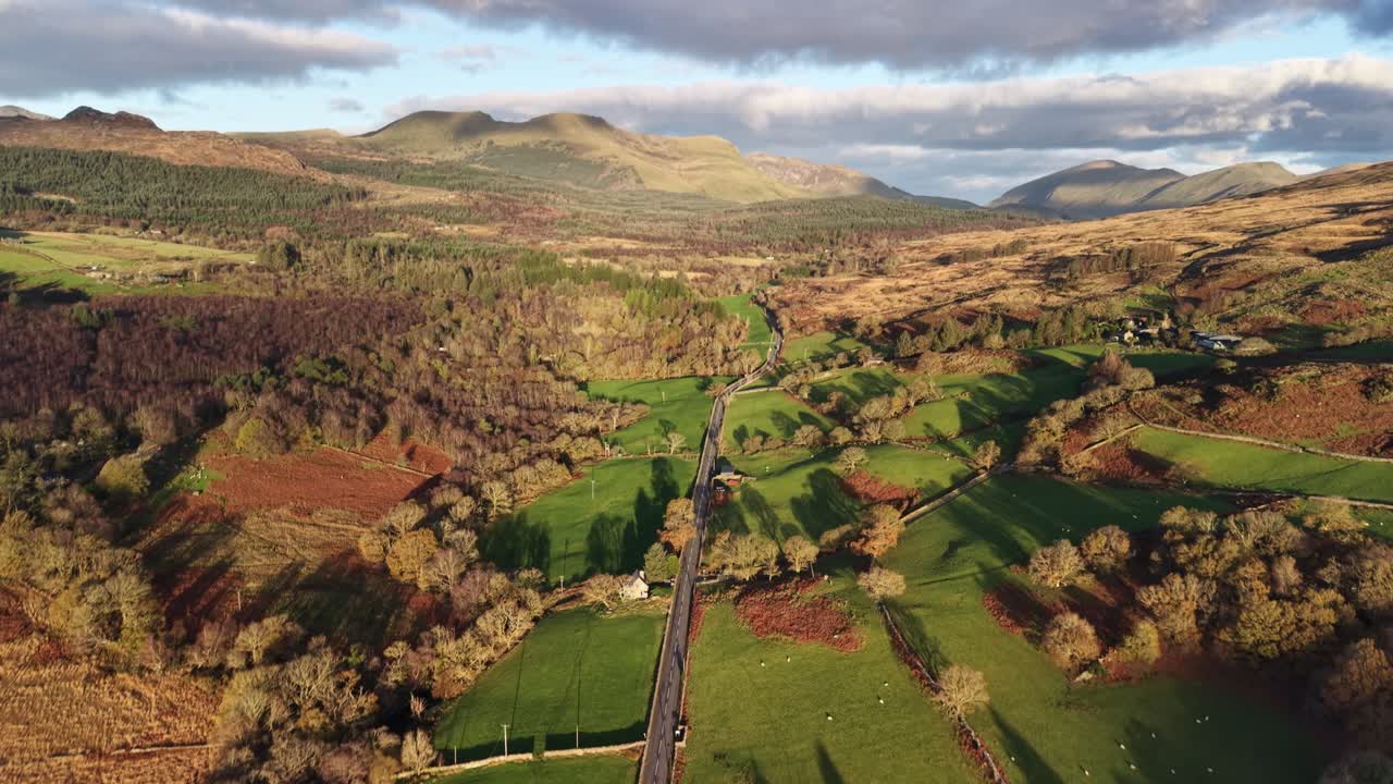 Splendido sorvolo di droni che si allontana da Beddgelert, panoramica verso il Monte Snowdon sullo sfondo durante l'ora d'oro, Galles del Nord, Regno Unito