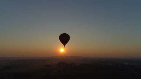 amanecer de un globo aerostático en una mañana nublada sobre tierras de cultivo amish visto por un dron