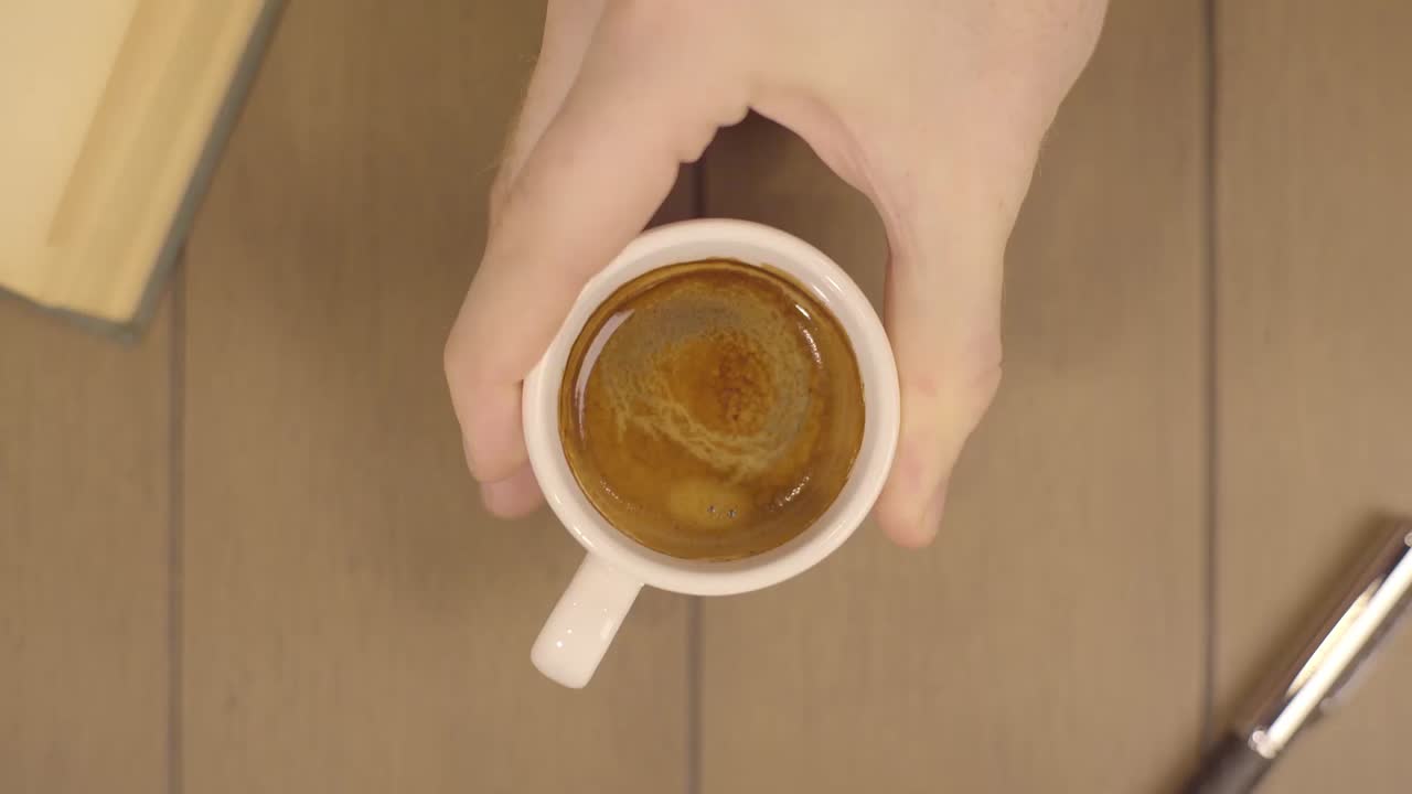 나무 테이블 위 에스프레소 한 잔 을 들고 있는 손