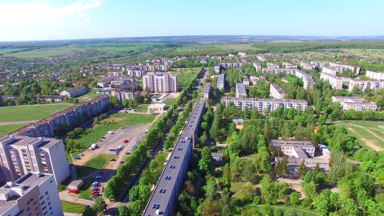 Cityscape with numerous blocks of flats. Picture of beautiful green town with rural outskirts. Aerial view.