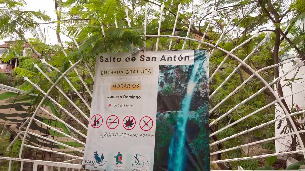 Cartel de entrada a la cascada Salto de San Antón rodeado de árboles y vegetación, marcando el acceso público a la atracción natural en Cuernavaca, Morelos, México.