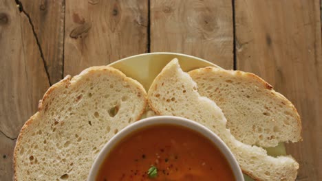 video of cream tomato soup in bowl on wooden table with bread