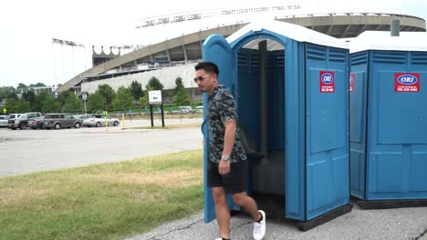 man walks out of a porta-potty