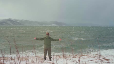 man open arms wide to feel ocean breeze with crashing waves