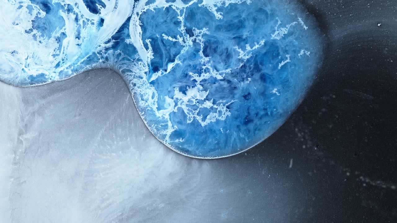 Blue alcohol ink spreads in water, forming dreamy abstract macro texture layers