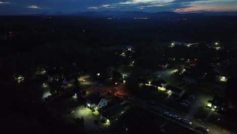 quiet american residential area at night. suburb district with one family houses in usa. aerial top down shot. dusk sunset scene at sky horizon. driving car on street with lighting lanterns.