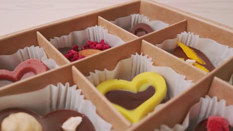 fabricación de cajas de regalos de caramelos de chocolate movimiento de cámara de primer plano extremo. chocolates variados confitería en fondo blanco cámara lenta, deslizador
