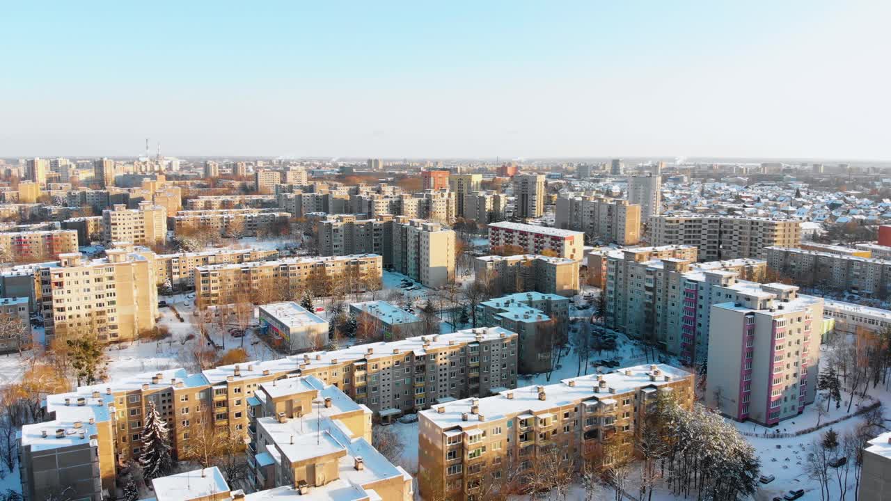 Luftaufnahme von Apartmenthäusern im Winter, verschneite Umgebung, sonniger Tag, direkter Überflug über die Gebäude, mit Zoom.
