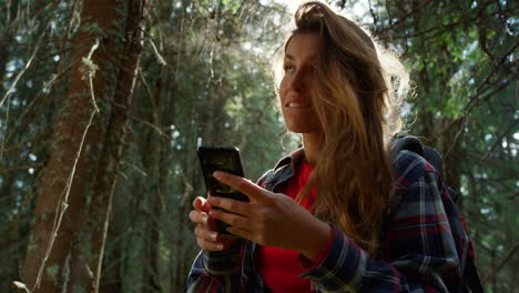 girl using smartphone in forest. hiker trying to find mobile network in woods
