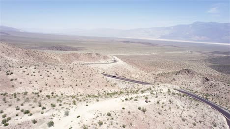 Drone-following-a-car-driving-on-a-desert-road-between-hills-in-4k