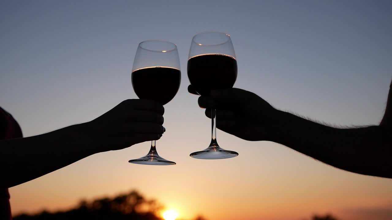 un vídeo en cámara lenta de dos copas de vino tintineando al atardecer
