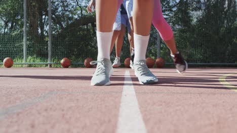 Diverse-female-basketball-team-training-with-male-coach-on-sunny-court,-copy-space,-slow-motion