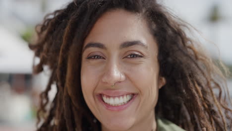 retrato de una hermosa mujer de raza mixta sonriendo alegremente disfrutando de un día soleado en vacaciones frente a la playa urbana