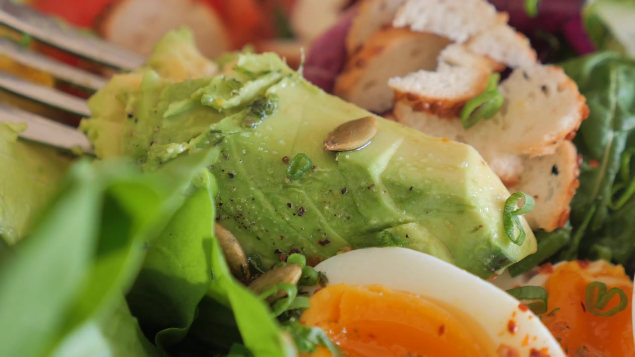 Spiser en deilig sunn salat med avokado og kokt egg