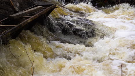 Bubbling-river-flowing-through-metal-sluice-in-slow-motion