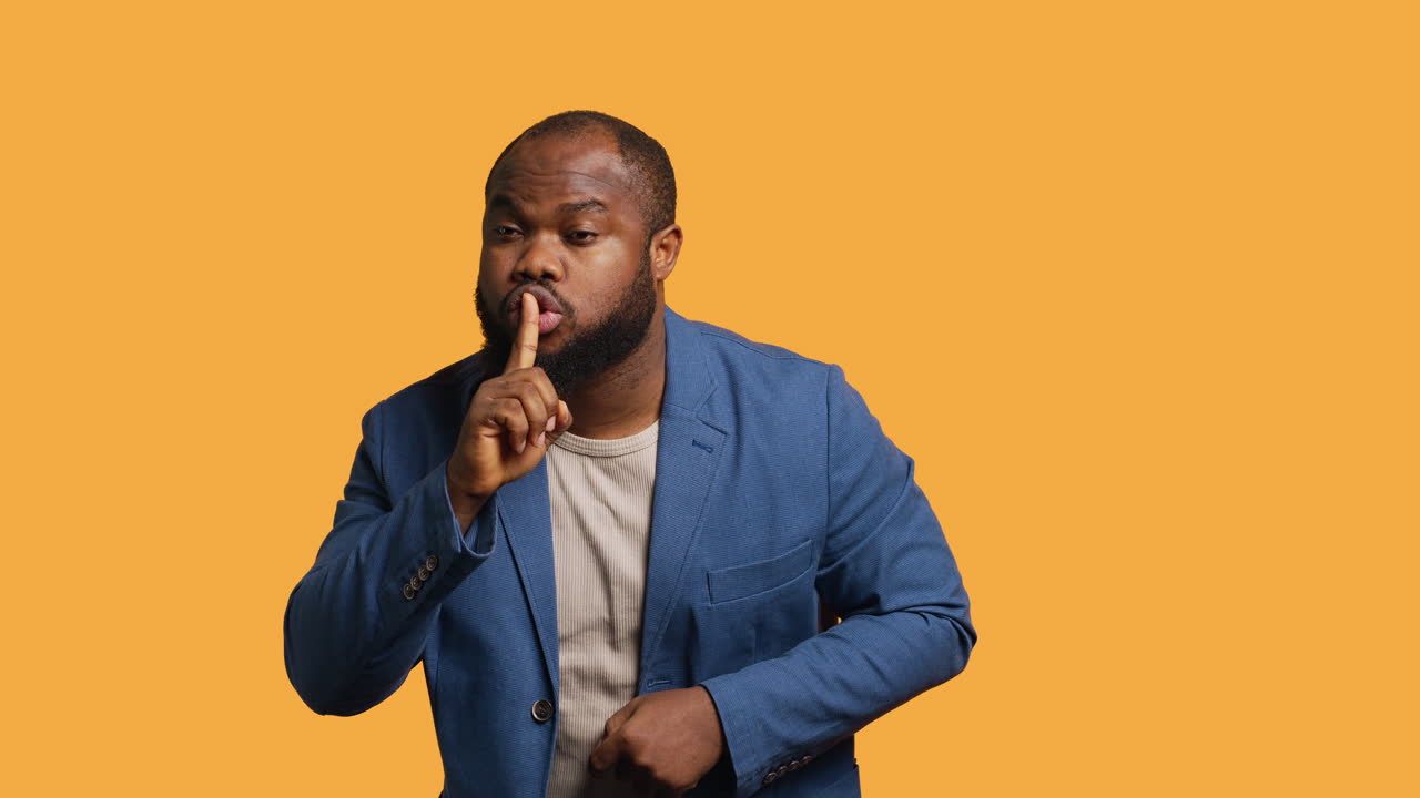 Man doing shushing hand gesturing, irritated by noise, studio background
