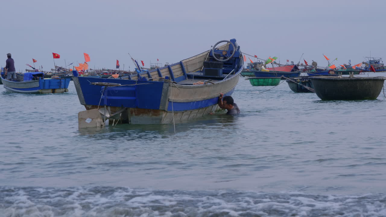 물 아래에 기대어 보트를 만지는 현지 남자의 추적 샷