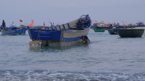 tracking shot of a local man leaning under the water and touching his boat