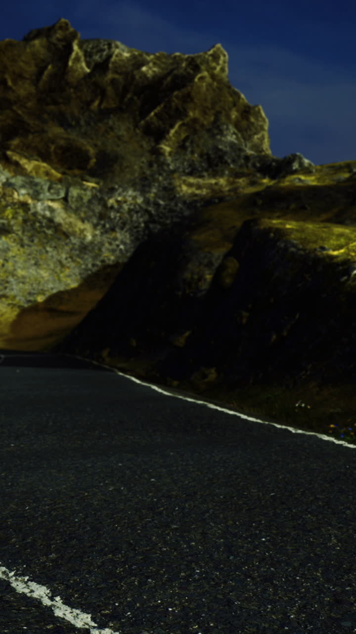 Winding road under a night sky near rocky hillside in a remote location