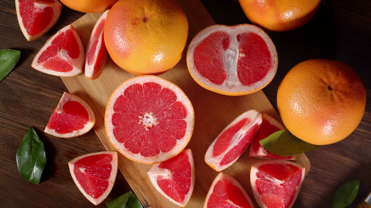 Pieces of ripe grapefruit with leaves on a cutting Board slowly rotate.