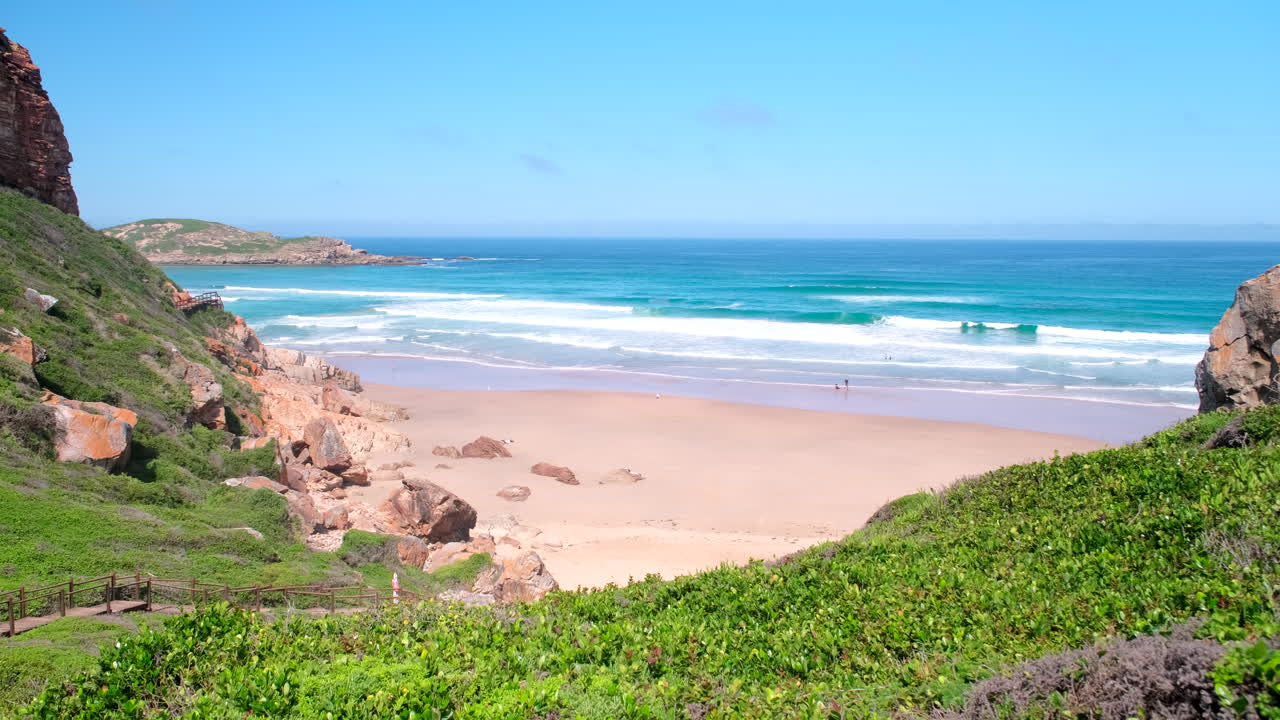 Vista panorâmica sobre uma praia intocada em direção à Ilha na Reserva Natural e Marinha de Robberg, enquanto as ondas quebram, Plettenberg Bay, África do Sul.