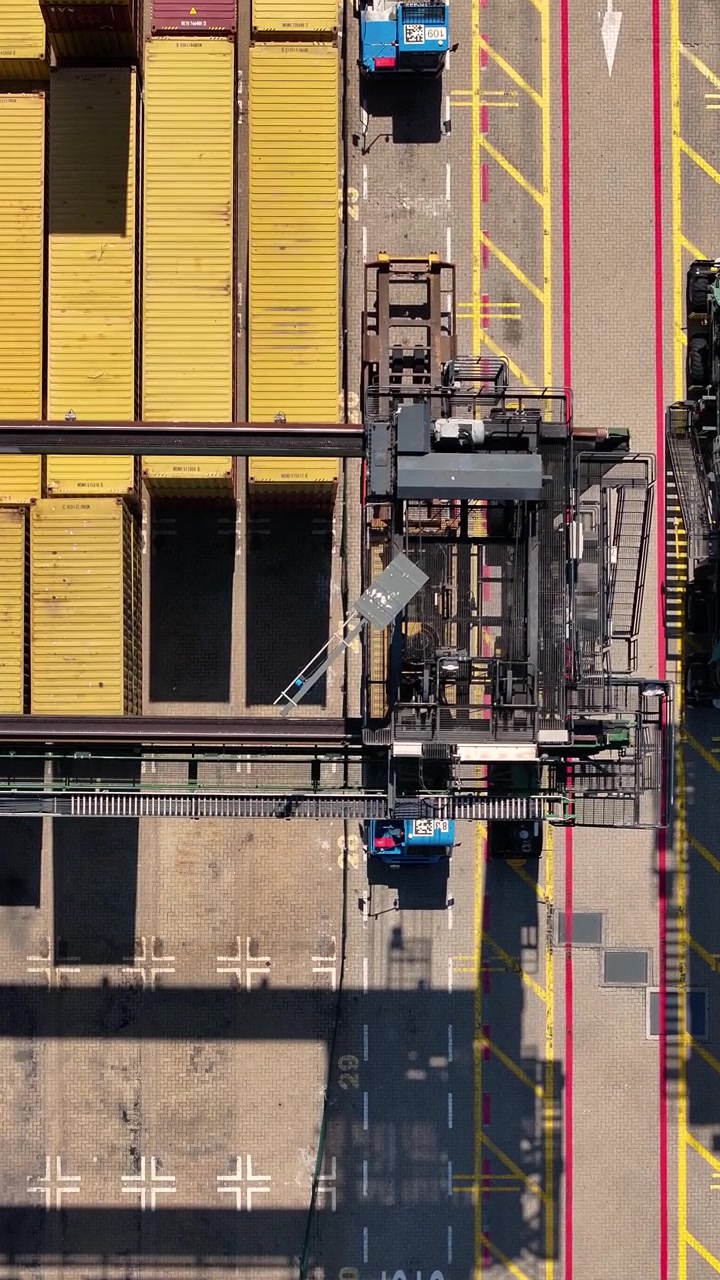 Container terminal shows multiple shipping containers and loading equipment. Focus on freight transportation in a busy cargo area during daylight hours, illustrating international trade operations.