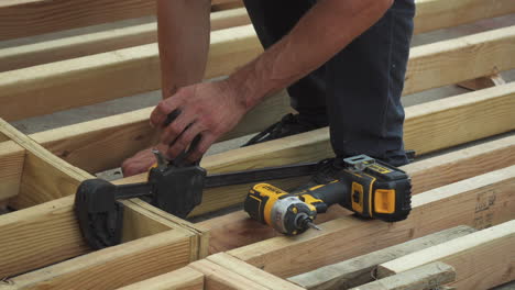 closeup of man's hands using tools to build diy skateboard ramp in backyard