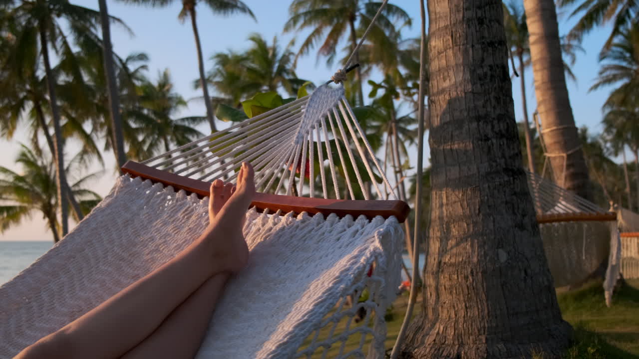 relajándose en una hamaca en una playa tropical al atardecer