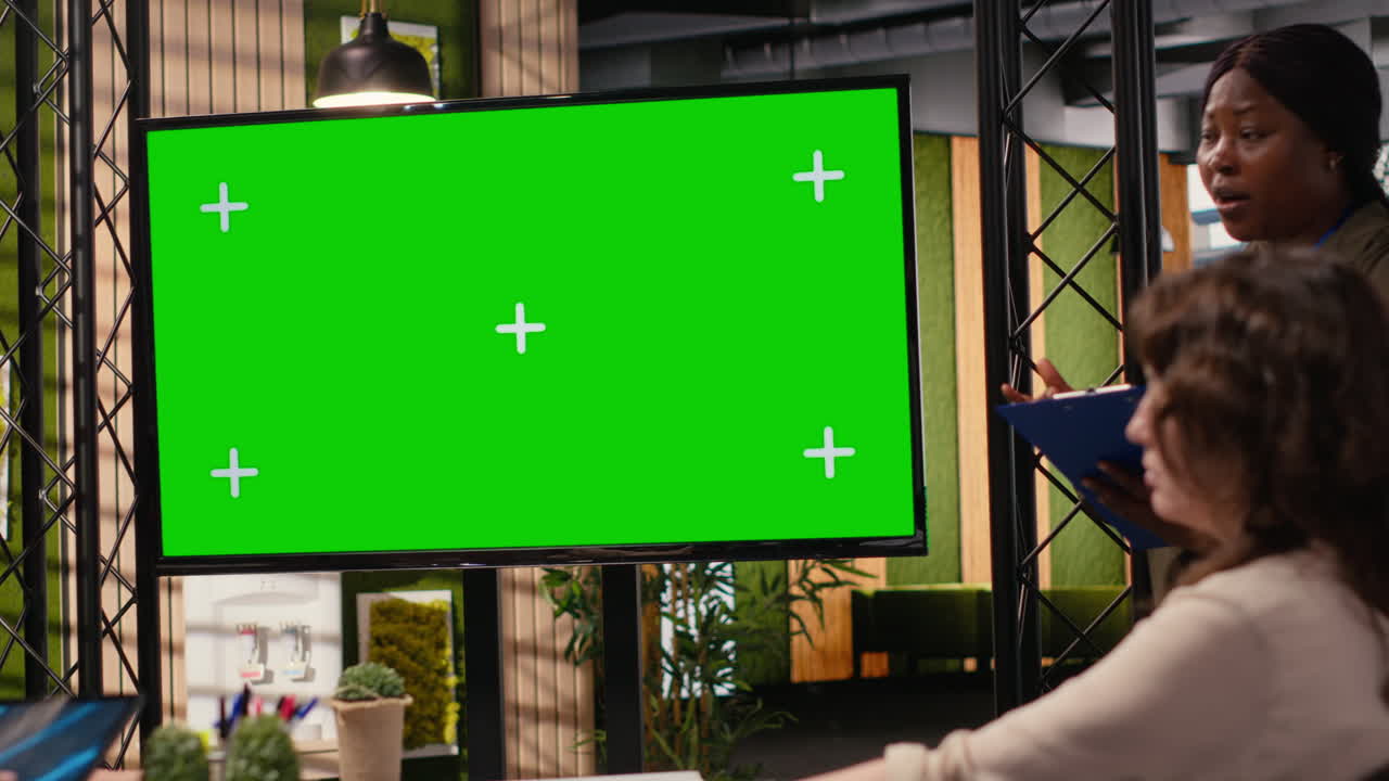 Diverse group of businesswomen collaborates near chroma key monitor