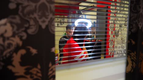 static shot seen through blinds of a woman been tattooed on the arm in a tattoo studio