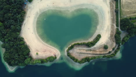 heart-shaped lake with beach and forest