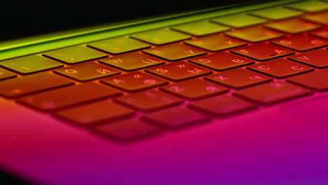 Rotating-close-up-of-a-modern-laptop-keyboard-and-trackpad-under-a-futuristic-neon-glow