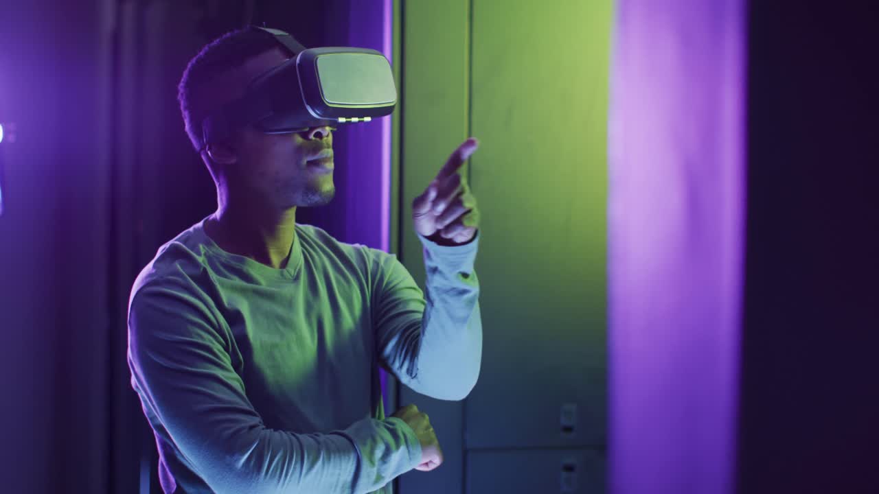tecnico informatico maschio afroamericano che usa le cuffie vr che lavora in una sala server aziendale
