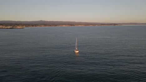 near sunset, this captivating drone footage circles around a boat elegantly maneuvering into the dock in santa cruz, california, casting a serene ambiance over the scene