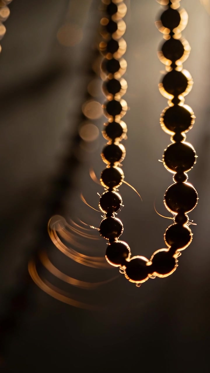 Video verticale: Catena di perline oscillante che si curva a U per la brezza della finestra, catturando polvere e luce calda