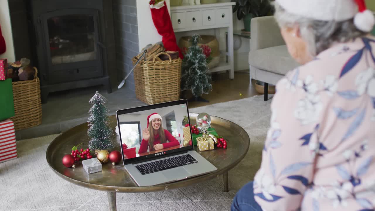 mujer mayor caucásica usando una computadora portátil para una videollamada de navidad con una mujer sonriente en la pantalla
