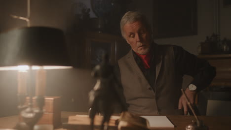 old passionate man writes a letter in his office at night