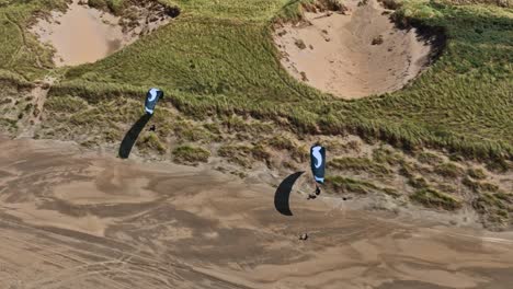 Aerial-tracking-shot-of-two-Dutch-paragliders-doing-some-dune-or-coastal-soaring