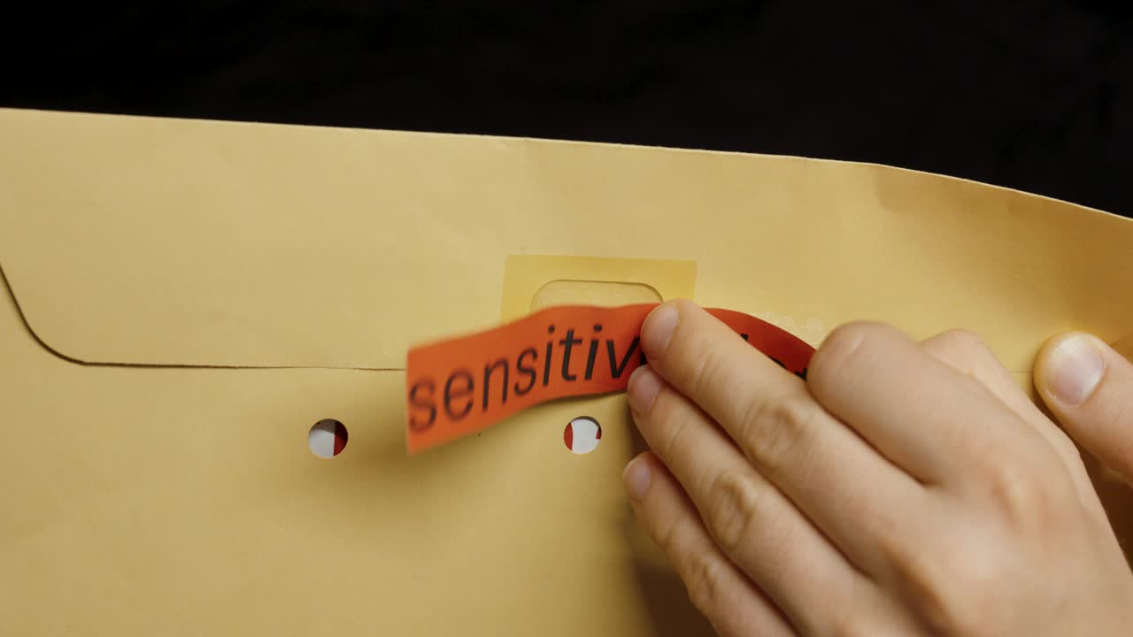 A person peels off the security label and opens a brown envelope labeled “sensitive data,” symbolizing unauthorized access and data privacy violation