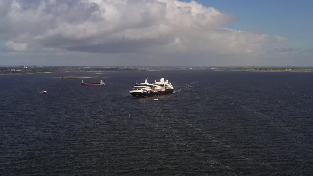 Wide aerial view of Galway Bay, featuring the anchored Azamara cruise and arriving Scotline cargo ship