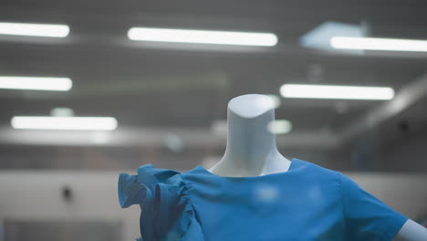 close-up of mannequin dressed in stylish blue top displayed in well-lit retail store with modern interior and soft blinking lights in background