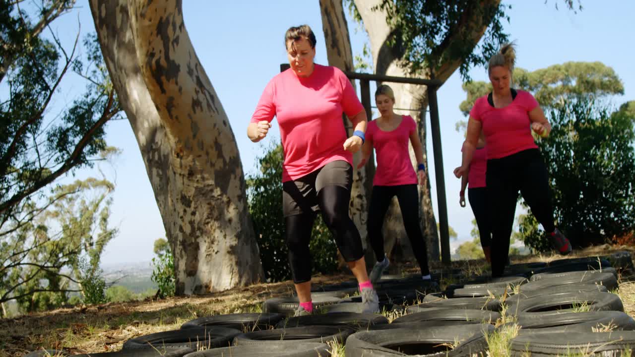 grupo de mujeres corriendo sobre neumáticos durante una carrera de obstáculos