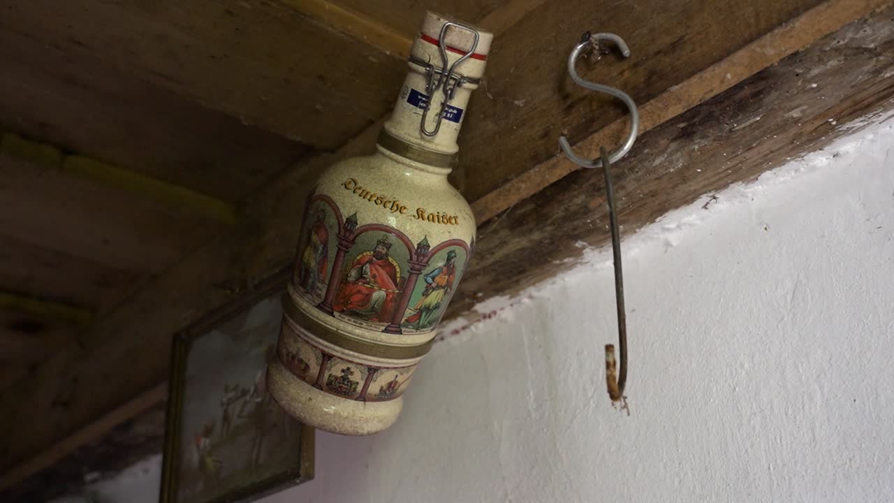 Antique German ceramic bottle with illustrations hanging under wooden shelf