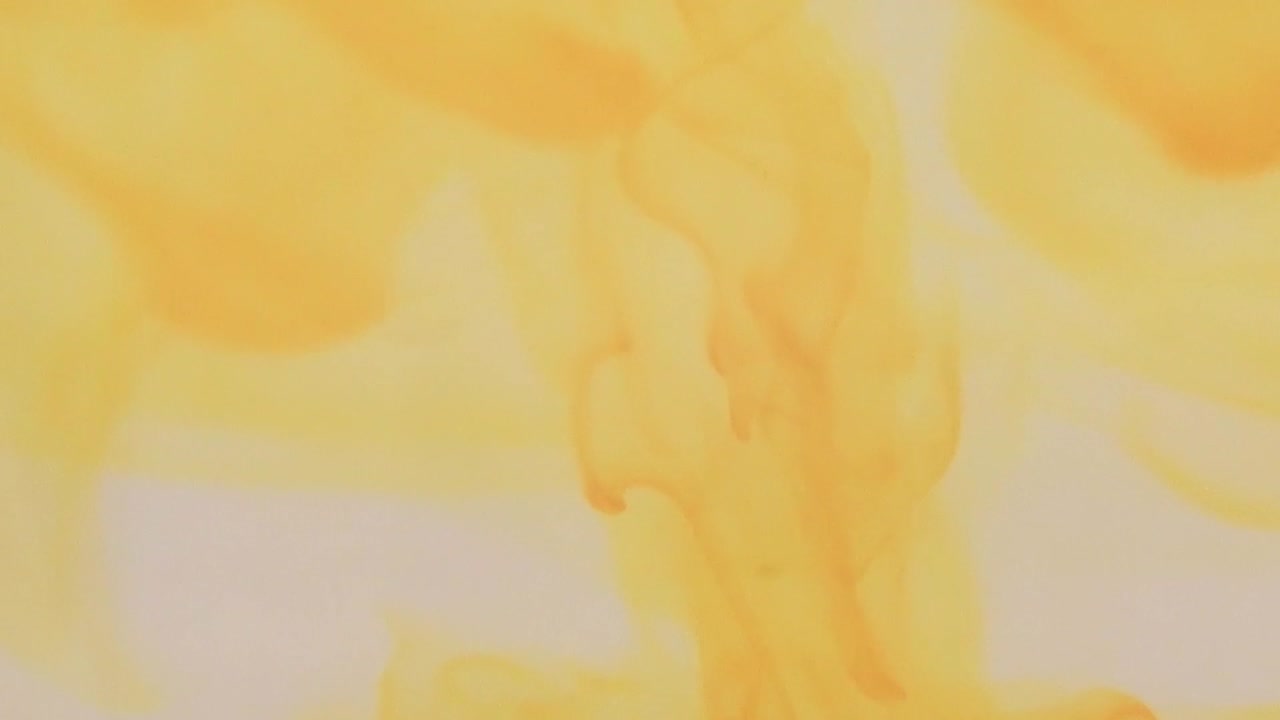 colorante alimentario amarillo arremolinándose en un recipiente con agua