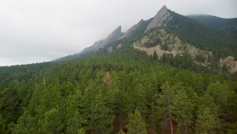 Aerial-ascent-of-Boulder-Flatirons-over-forest,-Colorado