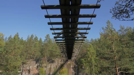 Floating-bridge-on-ropes-over-a-lake-or-a-stream-in-a-forest,-summer