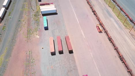 alice springs - australia. cinematic aerial flyover of freight containers at desert train station with pan up to reveal outback town and horizon beyond. filmed on dji mavic pro